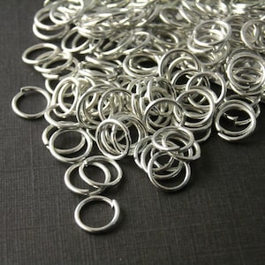 May include: A large pile of silver jump rings. The rings are small and round, and they are perfect for jewelry making.