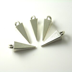 May include: Five silver triangle-shaped pendant charms with a loop at the top for attaching to jewelry.