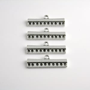 May include: Four silver-toned metal slider clasps with a loop at the top and a row of holes along the bottom.