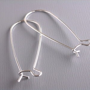 May include: A pair of silver earring hoops with a teardrop shape.