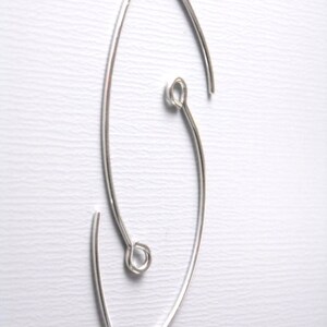 May include: Silver earring with a unique, asymmetrical design. The earring is made of a single piece of wire that is bent into a curved shape. The wire is then twisted to create a loop at the top of the earring.