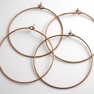 May include: Four gold-toned hoop earrings of different sizes. The hoops are made of thin wire and have a simple, elegant design.