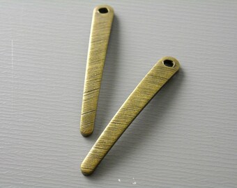 May include: Two gold-toned metal arrow-shaped charms with a hole at the top. The charms have a textured surface.