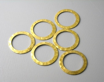 May include: Six gold-toned metal rings with a hammered texture. The rings are all different sizes and are arranged in a semi-circle.
