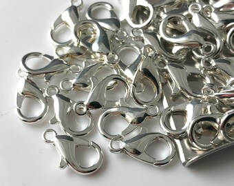 May include: A pile of silver-toned lobster claw clasps, commonly used for jewelry making.