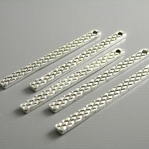 May include: Five silver metal bar pendants with a diamond pattern and a hole at the top.