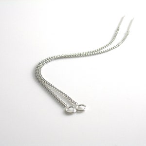 May include: A pair of silver chain earrings with a simple design. The earrings are long and dangle from the earlobe.
