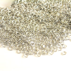 May include: A large pile of silver jump rings. The rings are small and round, and they are perfect for jewelry making.