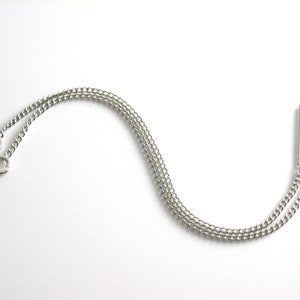 May include: Two silver chains with small circular clasps at one end and a silver loop at the other end.