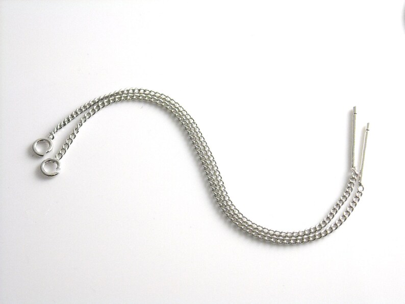 May include: Two silver chains with small circular clasps at one end and a silver loop at the other end.