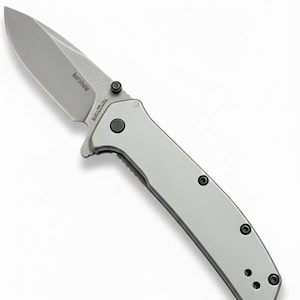 May include: A silver folding knife with a partially serrated blade. The knife has a gray handle with black screws and the brand name "Kershaw" is visible on the blade. The knife is designed for everyday carry.