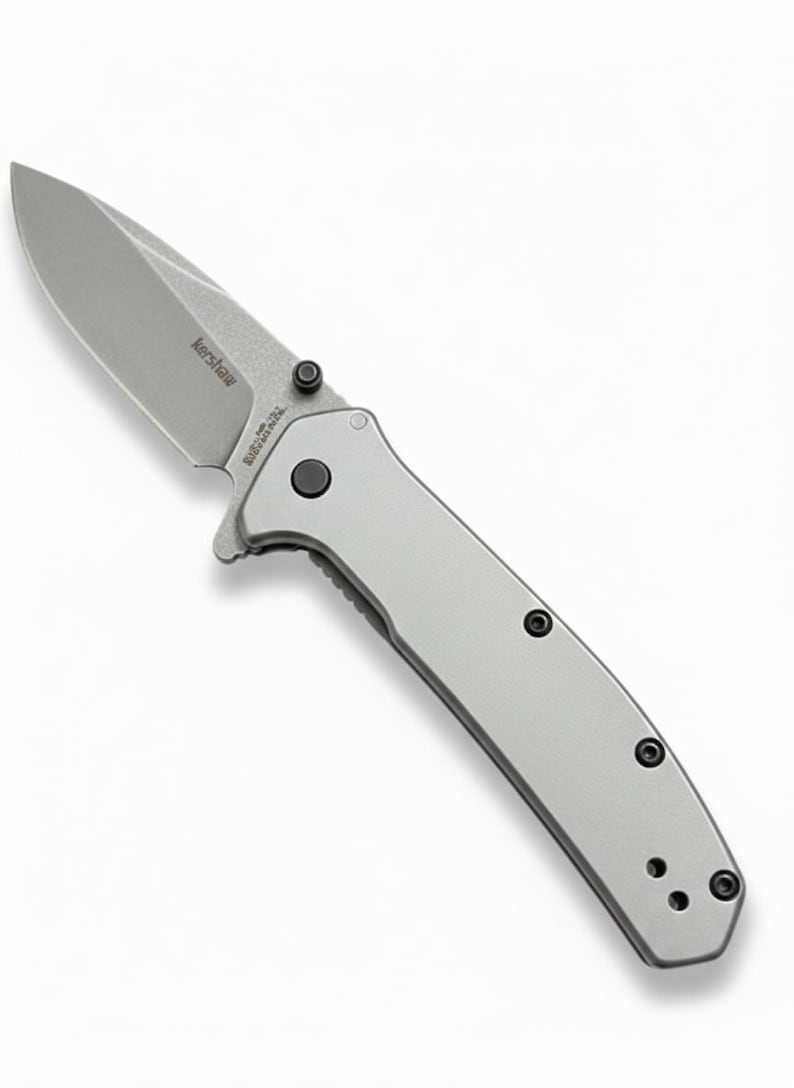 May include: A silver folding knife with a partially serrated blade. The knife has a gray handle with black screws and the brand name "Kershaw" is visible on the blade. The knife is designed for everyday carry.