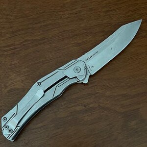 May include: A silver folding knife with a partially serrated blade. The knife has a clip for pocket carry and a textured handle. The blade is marked with the text "1340 EA Patented".