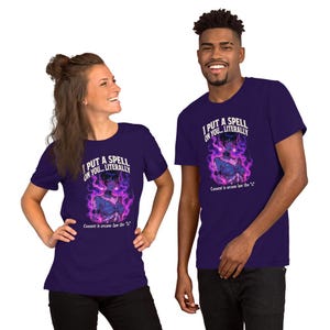 May include: Two people wearing matching purple t-shirts. The shirts feature the text "I PUT A SPELL ON YOU... LITERALLY" above an illustration of a character surrounded by purple flames. The phrase "Consent is arcane law tho" is below the illustration.