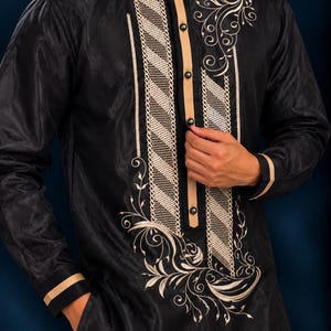May include: A black long-sleeved shirt featuring a central beige button placket, a mandarin collar, and intricate beige embroidery. The front panel displays diagonal textured stripes and swirling floral patterns on a dark fabric.