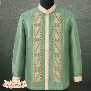 May include: A long-sleeved sage green shirt featuring a mandarin collar and a button-down front placket in a light peach tone. The front panels are decorated with vertical embroidered bands in peach and silver, showcasing geometric patterns.