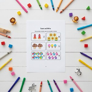 May include: A white educational worksheet titled Count and Write featuring six boxes with illustrations of rockets, flowers, mushrooms, ice cream cones, beach balls, and seashells, surrounded by colorful crayons and small animal figurines.