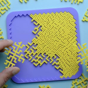 May include: A square purple tray with a recessed area containing a complex yellow interlocking maze puzzle. Several additional yellow geometric puzzle pieces with jagged edges are scattered around the tray, waiting to be fitted into the grid.