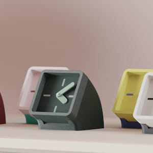 May include: A collection of modern, minimalist alarm clocks in various colors, including rust, pink, dark gray, yellow, and white. Each clock has a square face with a single hand and a simple, geometric design. The clocks are displayed on a white surface.