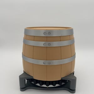 Peut inclure: Un petit tonneau en bois brun avec des bandes métalliques argentées. Le tonneau repose sur une base décorative gris foncé. Le tonneau a un dessus brun clair et est conçu pour contenir des liquides.