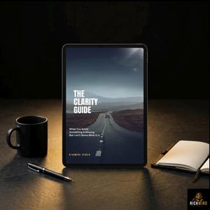May include: A black tablet displays "The Clarity Guide" with a road image. A black mug, pen, and open notebook are on a dark surface. The text reads "When You Know Something Is Missing But Can't Name What It Is."