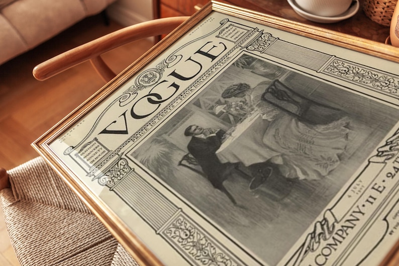 Op de afbeelding: Een ingelijste vintage Vogue tijdschriftomslag uit juli 1893, met een zwart-wit illustratie van twee personen aan een tafel. De print bevat de tekst VOGUE, PRICE 10 CENTS, FOUR DOLLARS A YEAR en 4 JULY 1893, geplaatst in een gouden lijst.