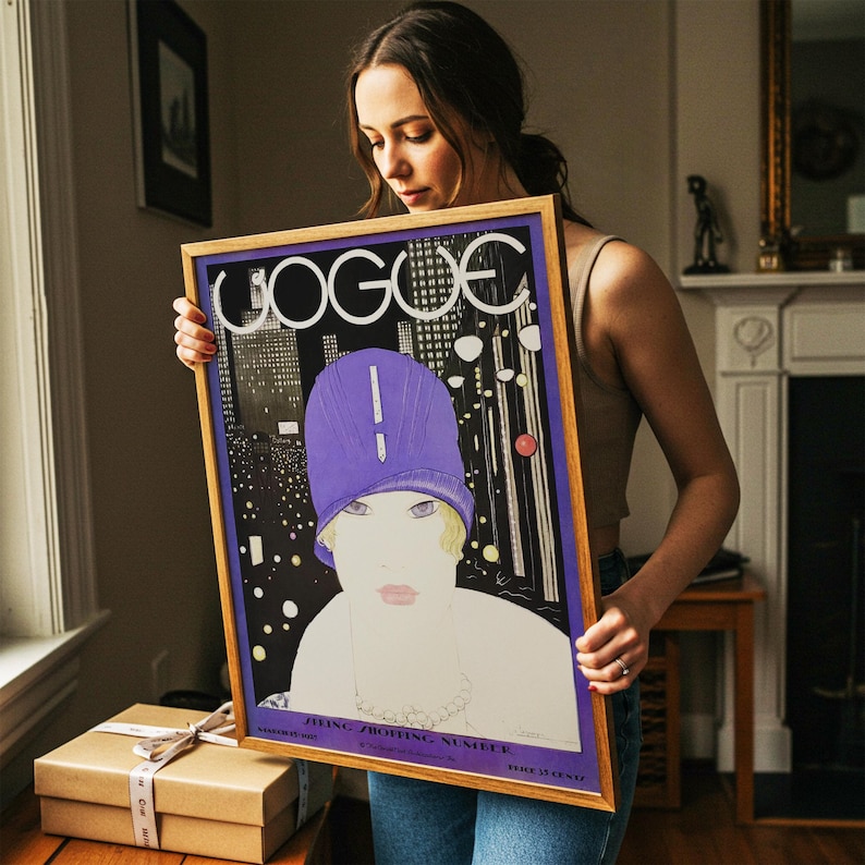 May include: A framed vintage Vogue magazine cover print featuring a stylized illustration of a person wearing a purple cloche hat against a dark city skyline background. The text VOGUE is printed in large white letters at the top of the rectangular poster.