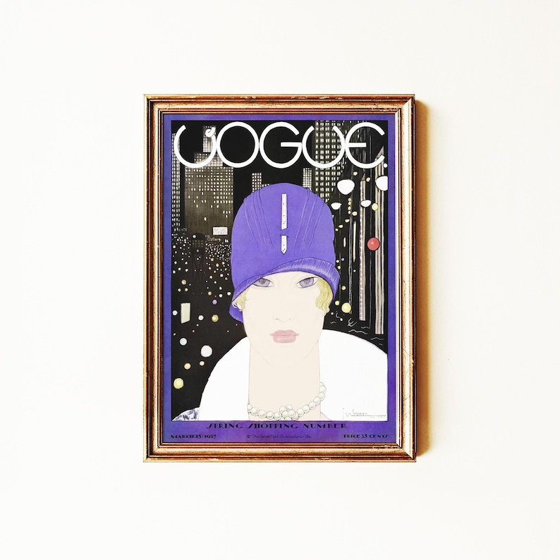 May include: A framed vintage Vogue magazine cover print featuring a stylized illustration of a person wearing a purple cloche hat and a white coat against a dark city skyline. The text reads VOGUE and SPRING SHOPPING NUMBER in white lettering.