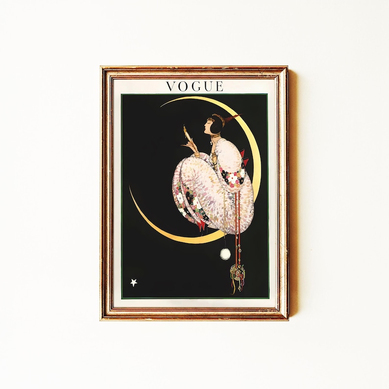 以下が含まれることがあります： 額装されたヴィンテージVogue誌の表紙アート。黒い背景に三日月の上に座る女性が描かれています。女性は花柄のアクセントが付いた詳細なドレスを着ています。フレームは金色の縁取りです。