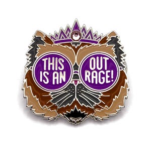 May include: A metal enamel pin shaped like a cat head wearing a purple crown and round purple glasses. The glasses feature the white text THIS IS AN on the left lens and OUT RAGE! on the right lens. The cat is colored in shades of brown, black, and white.