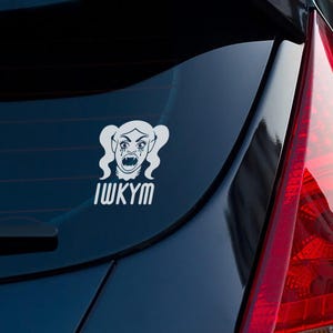May include: White vinyl car decal featuring a stylized vampire-like character with pigtails, fangs, and tears. The text "IWKYM" is below the graphic. The decal is affixed to the rear window of a dark blue car.