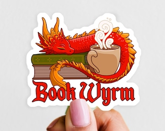 May include: A die-cut sticker featuring a red dragon with orange accents resting on a stack of two books next to a steaming mug of coffee. The text "Book Wyrm" is printed in a bold red gothic-style font at the bottom of the illustration.