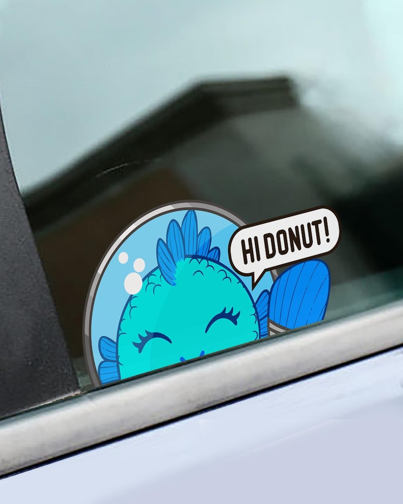 May include: A circular sticker featuring a bright blue fish inside a glass bowl. The fish has a spiky fin, closed eyes, and is waving one fin. A white speech bubble extends from the bowl with the black text HI DONUT! printed inside.