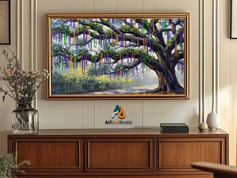 May include: A framed painting depicts a large tree adorned with colorful beads, reminiscent of a festive celebration. The artwork features a road, fence, and buildings in the background, with a gold frame. The painting is displayed above a wooden cabinet.