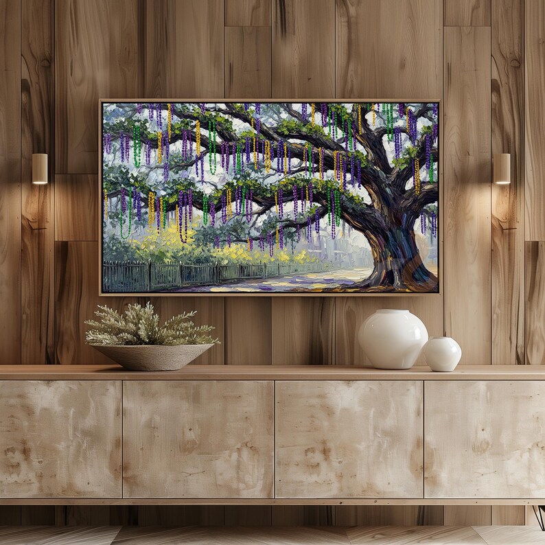 May include: A framed painting of a large tree adorned with colorful beads, likely depicting a Mardi Gras scene. The artwork features a detailed depiction of the tree's branches and foliage, with a road and fence in the background. The color palette includes greens, purples, and yellows.