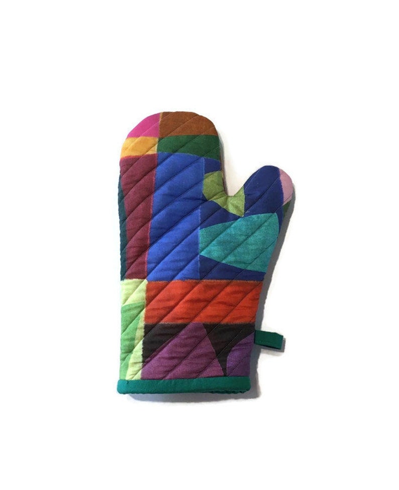 This colorful modern oven mitt makes a bold statement with large patches of saturated colors - blues, oranges, purple, green, pink, yellow. The handmade oven mitt is quilted. The binding and hanging loop are green.