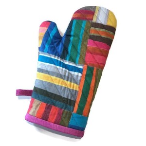 May include: A colorful oven mitt with a patchwork design. The mitt features a variety of vertical stripes in shades of blue, yellow, red, orange, and green. The cuff is trimmed with a bright pink fabric, and a pink loop is attached.