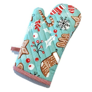 May include: A quilted oven mitt with a light blue background and a Christmas-themed pattern. The pattern includes gingerbread men, candy canes, snowflakes, and holly. The mitt has a red and white striped trim.