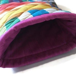 May include: A quilted oven mitt with a vibrant, multicolored striped exterior. The interior is a deep purple, and the cuff is a matching purple. The mitt is designed to protect hands from heat.