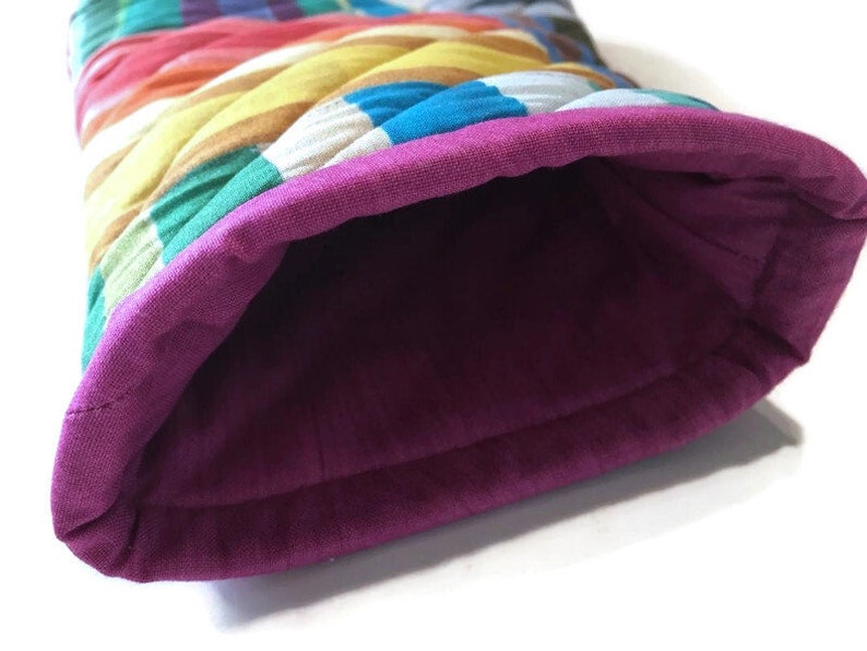 May include: A quilted oven mitt with a vibrant, multicolored striped exterior. The interior is a deep purple, and the cuff is a matching purple. The mitt is designed to protect hands from heat.