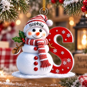 Könnte beinhalten: Ein transparenter Acryl-Weihnachtsanhänger mit einem Schneemann, der eine rot-weiß gestreifte Mütze mit dem Namen Sophia, einen passenden Schal und einen großen roten Buchstaben S mit weißen Schneeflocken trägt, an einer goldenen Kordel.