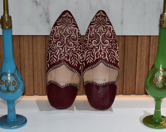 Babuchas marroquíes en piel burdeos, hechas a mano, con motivos tradicionales grabados, zapatillas artesanales, cómodas y elegantes.