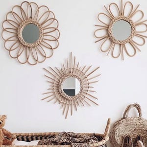 以下が含まれることがあります： 白いドレッサーの上に、花とサンバーストのデザインの3つの装飾的な籐の鏡が吊るされています。 黒と白の模様の織りバスケットには、ヒョウ柄の毛布が入っています。 テディベア、バッグ、靴、木製のおもちゃが保育園の装飾を完成させます。