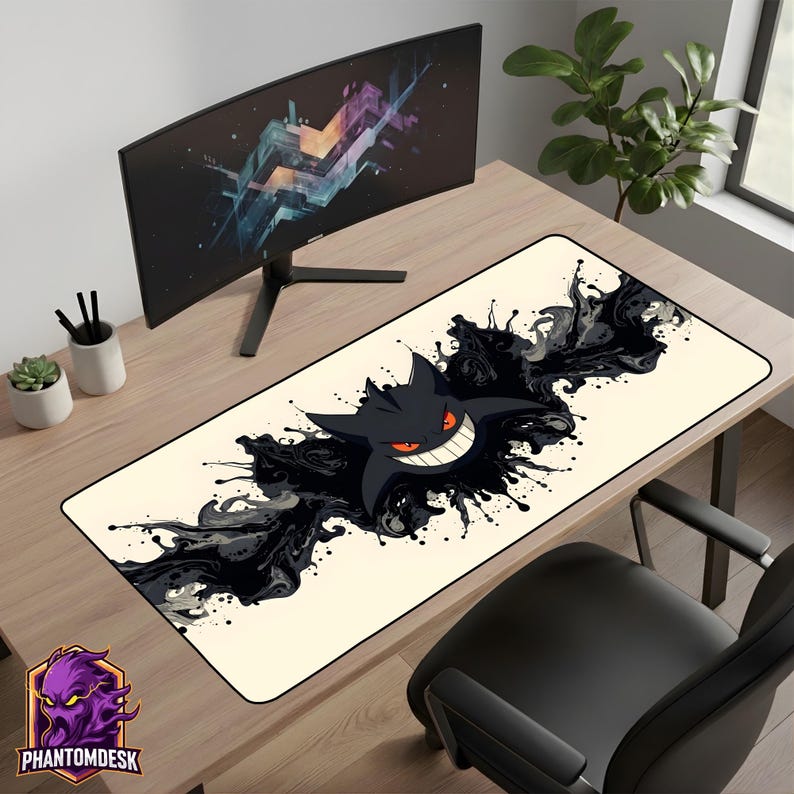 May include: A rectangular desk mat with a black cartoon character with a wide grin and red eyes, set against a cream background with black ink-like splatters. The mat is on a wooden desk, with a computer monitor and office accessories.
