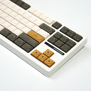 May include: A white mechanical keyboard with a variety of keycap colours, including cream, olive green, and mustard yellow. The keyboard has a compact layout with function keys and arrow keys. The keycaps are a mix of colours and shapes.