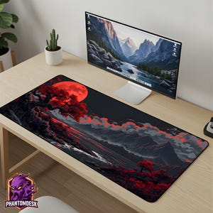 Puede incluir: Alfombrilla de escritorio rectangular negra y roja con un diseño de paisaje con una gran luna roja, árboles y montañas. La alfombrilla tiene el texto "PHANTOMDESK" y un logotipo morado. Un monitor de ordenador está encima.