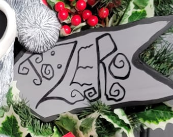 May include: A gray and black Christmas wreath with a white skull and a sign that says "Zero" in a black, stylized font.