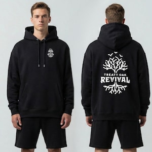 May include: Black hoodie with the text "REVIVAL" and a tree graphic on the front and back. The hoodie has a drawstring hood and a front pocket. The back of the hoodie features the words "TREATY OAK" above "REVIVAL".