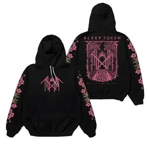 May include: A black hooded sweatshirt featuring a pink graphic on the front and back. The front displays a geometric logo, while the back shows the text SLEEP TOKEN above a detailed illustration of a path through trees. Pink cherry blossoms decorate both sleeves.