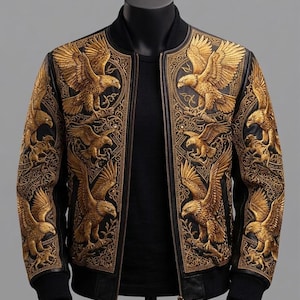 May include: A black bomber jacket featuring intricate gold-colored embroidery of eagles and ornate scrollwork patterns across the front panels and sleeves. The jacket has a ribbed black collar, cuffs, and hem, with a central front zipper closure.